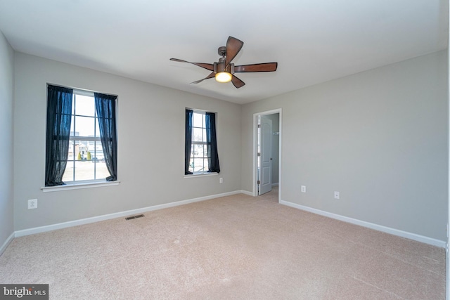 spare room featuring visible vents, baseboards, light colored carpet, and a ceiling fan