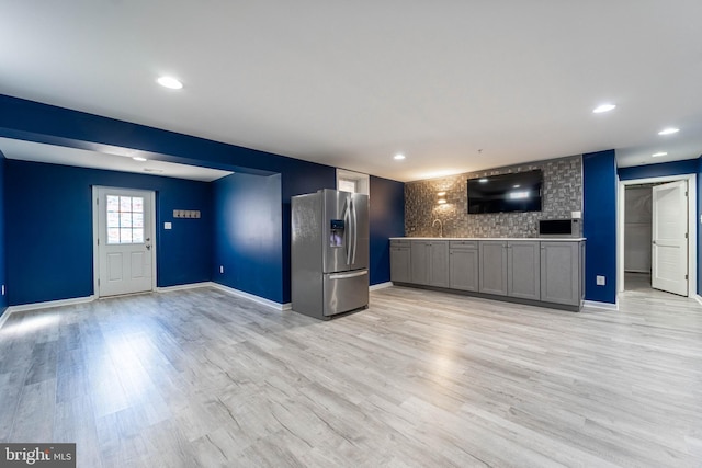 interior space with baseboards, stainless steel fridge with ice dispenser, recessed lighting, light wood-style floors, and a sink