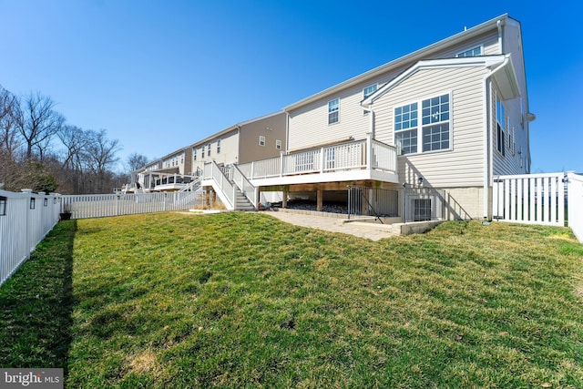 back of property with a deck, stairs, a fenced backyard, and a lawn