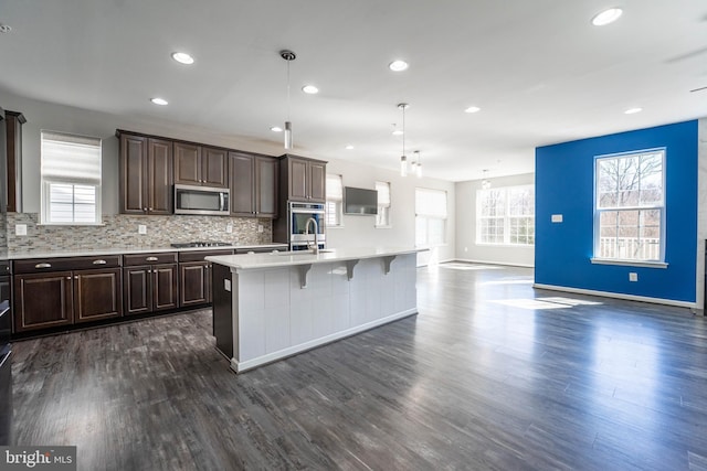 kitchen with dark brown cabinets, backsplash, appliances with stainless steel finishes, and light countertops