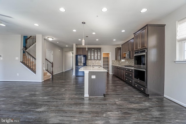 kitchen with a sink, decorative backsplash, light countertops, dark brown cabinets, and appliances with stainless steel finishes