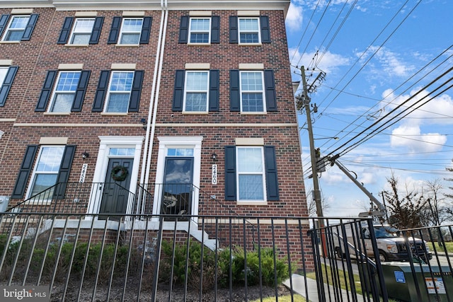 townhome / multi-family property with brick siding and a fenced front yard