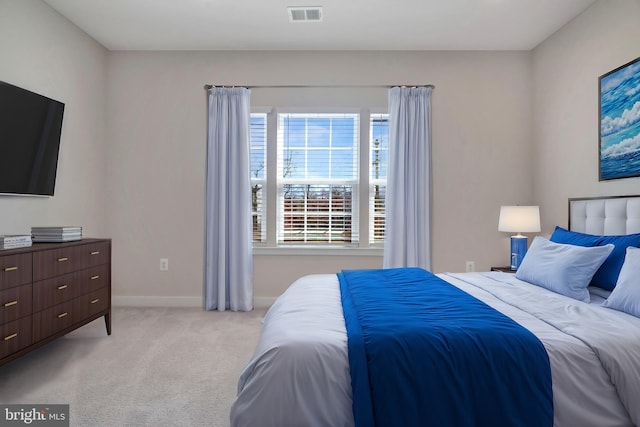 bedroom with baseboards, visible vents, and light carpet