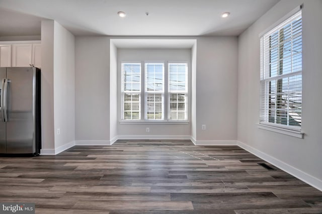 unfurnished dining area featuring visible vents, plenty of natural light, baseboards, and dark wood finished floors