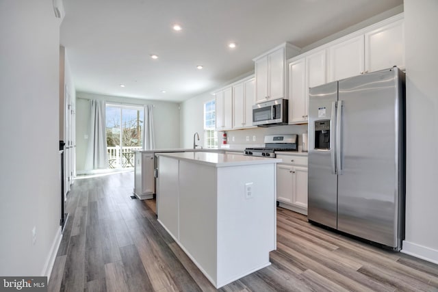 kitchen featuring wood finished floors, a kitchen island, appliances with stainless steel finishes, and white cabinets