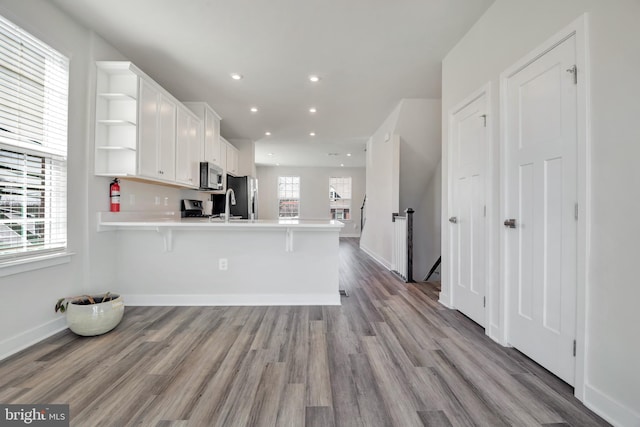 kitchen with light countertops, appliances with stainless steel finishes, a peninsula, white cabinets, and open shelves