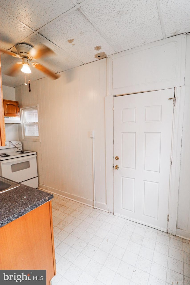 kitchen with ceiling fan, a paneled ceiling, under cabinet range hood, light floors, and white electric range oven