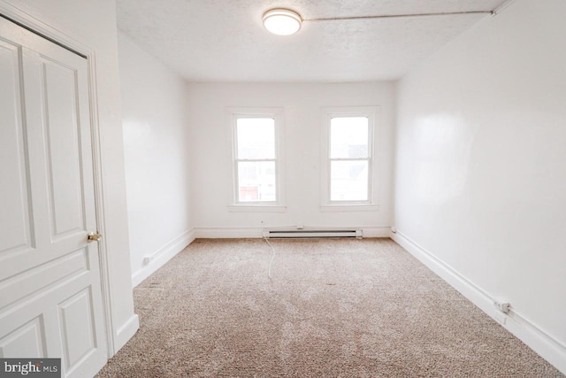 carpeted spare room featuring baseboards, a baseboard heating unit, and a textured ceiling