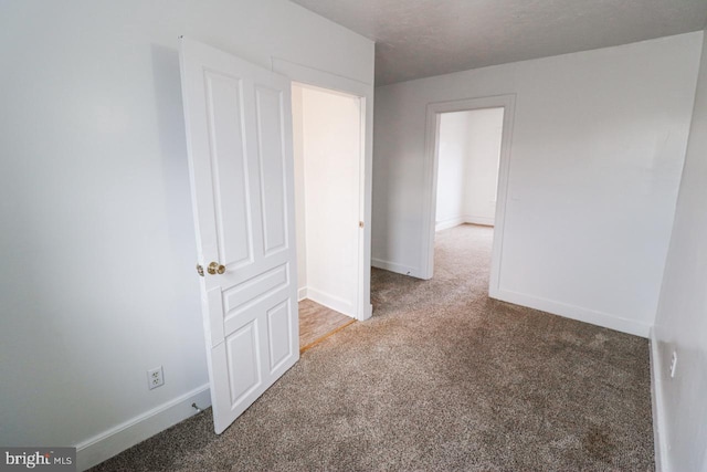 carpeted empty room featuring baseboards