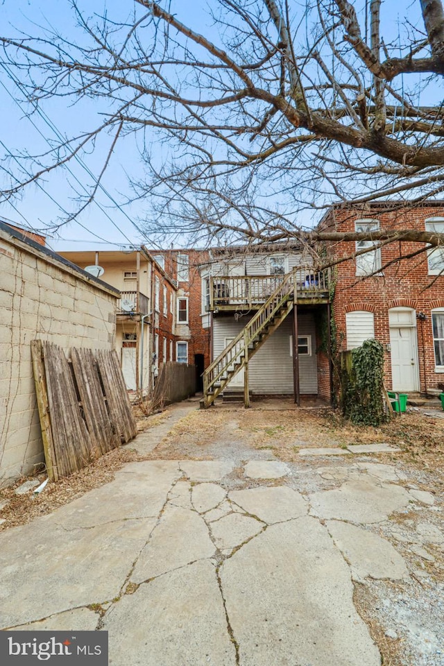 rear view of house with stairs, fence, a deck, and brick siding