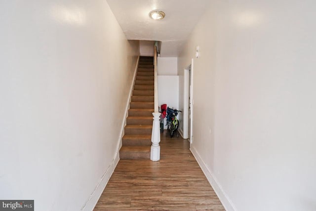 staircase featuring baseboards and wood finished floors