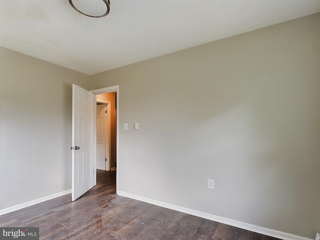 empty room featuring dark wood-type flooring and baseboards