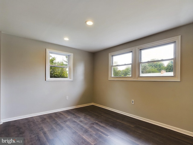 empty room with dark wood-style floors, baseboards, and recessed lighting