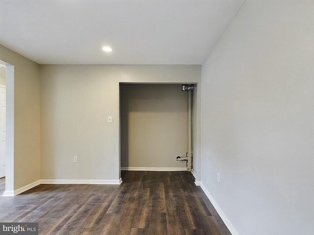 spare room with baseboards, dark wood finished floors, and recessed lighting