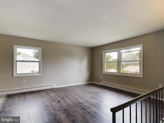 spare room featuring a baseboard radiator, dark wood-style flooring, a healthy amount of sunlight, and baseboard heating