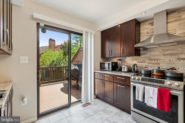 kitchen featuring dark brown cabinetry, decorative backsplash, wall chimney exhaust hood, light stone countertops, and stainless steel appliances