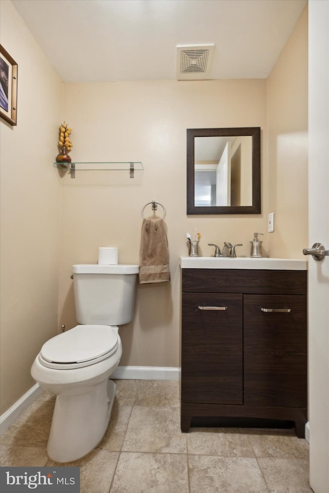 half bath with toilet, baseboards, visible vents, and vanity