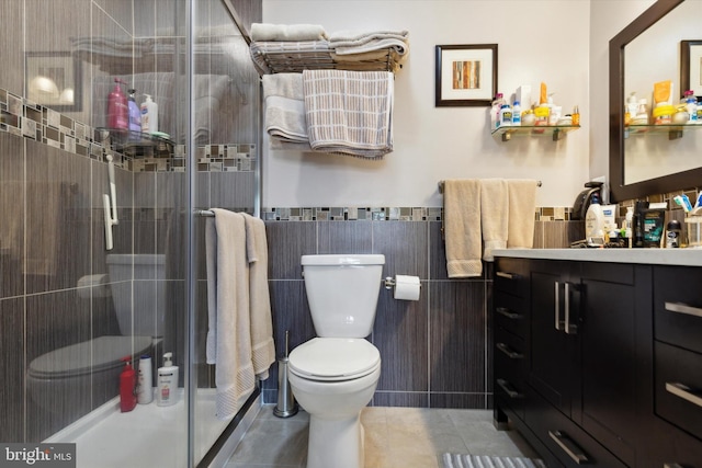 full bathroom featuring toilet, tile patterned floors, vanity, a shower stall, and tile walls