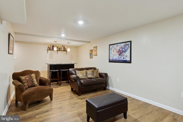 living area featuring baseboards, light wood finished floors, and a bar