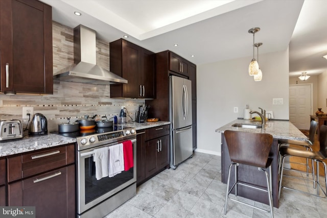 kitchen with appliances with stainless steel finishes, a kitchen breakfast bar, a sink, wall chimney range hood, and backsplash