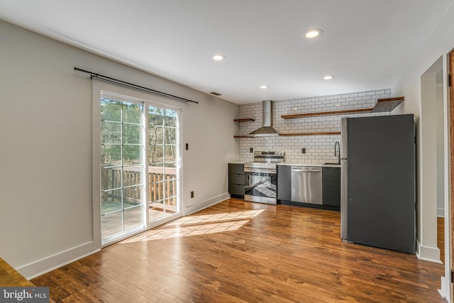 kitchen featuring backsplash, dark wood-type flooring, wall chimney range hood, appliances with stainless steel finishes, and open shelves