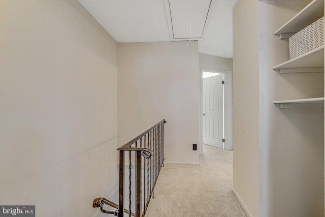 corridor featuring baseboards, an upstairs landing, attic access, and carpet