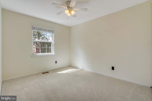 carpeted empty room with visible vents, baseboards, and a ceiling fan