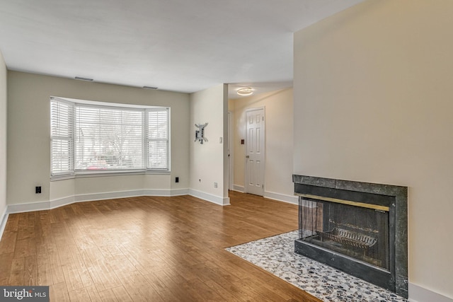 living room featuring visible vents, wood finished floors, a multi sided fireplace, and baseboards