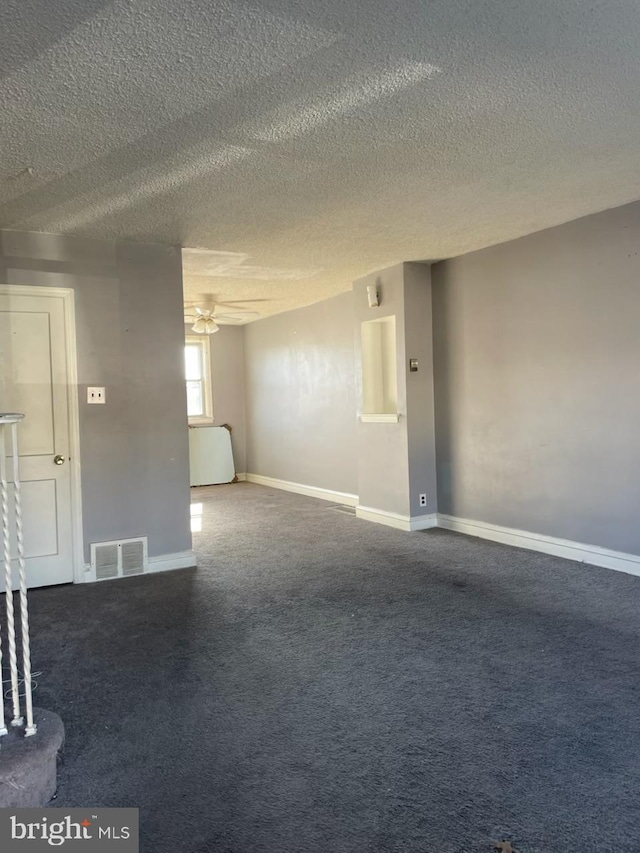 carpeted empty room with a textured ceiling, a ceiling fan, visible vents, and baseboards