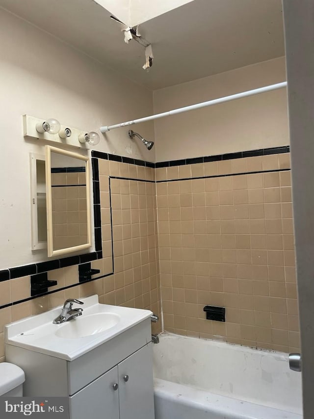 full bath featuring tile walls, toilet, vanity, and shower / bathing tub combination