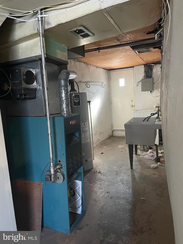 utility room with water heater, visible vents, heating unit, and a sink