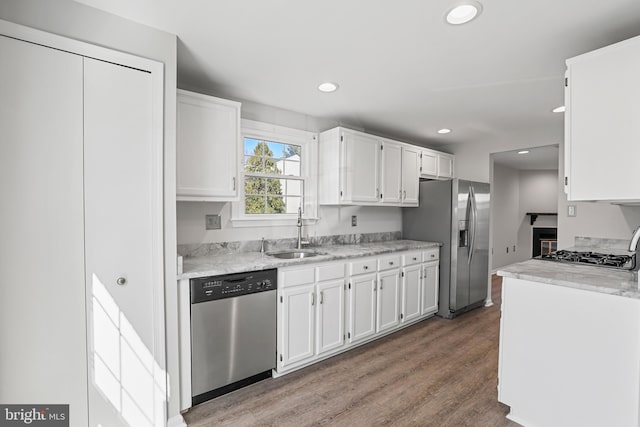 kitchen featuring a sink, wood finished floors, white cabinetry, stainless steel appliances, and light countertops