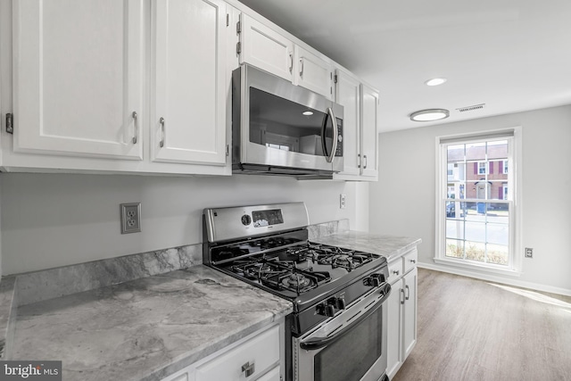 kitchen with white cabinetry, light wood-style flooring, visible vents, and appliances with stainless steel finishes