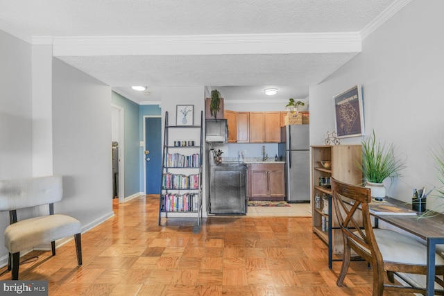 kitchen featuring a textured ceiling, baseboards, light countertops, ornamental molding, and freestanding refrigerator