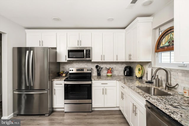 kitchen with light stone counters, visible vents, a sink, appliances with stainless steel finishes, and white cabinetry