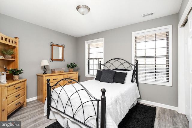 bedroom featuring baseboards, visible vents, and light wood finished floors