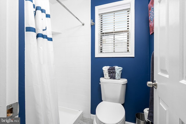 bathroom with a stall shower, toilet, and baseboards