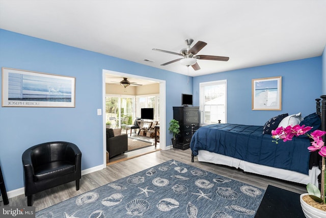 bedroom featuring visible vents, multiple windows, baseboards, and wood finished floors