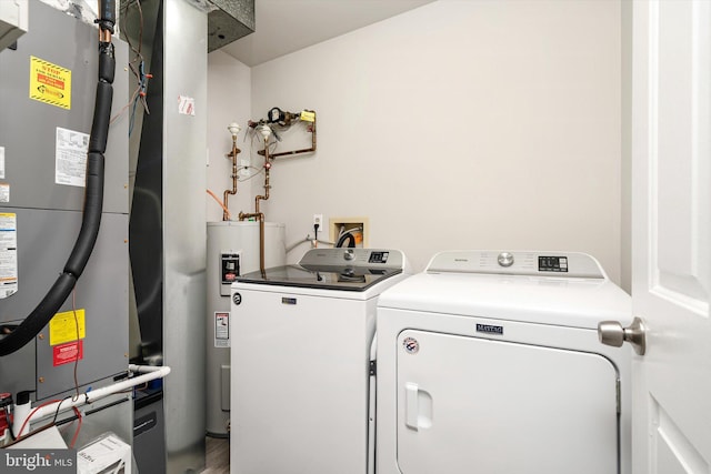 laundry room with heating unit, wood finished floors, washing machine and dryer, water heater, and laundry area