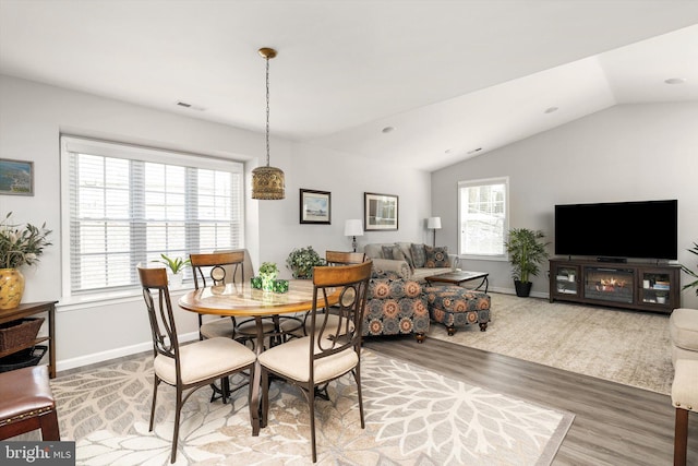 dining area featuring visible vents, baseboards, light wood-style flooring, and vaulted ceiling