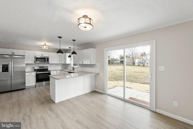 kitchen with appliances with stainless steel finishes, light wood-style floors, a peninsula, and decorative backsplash