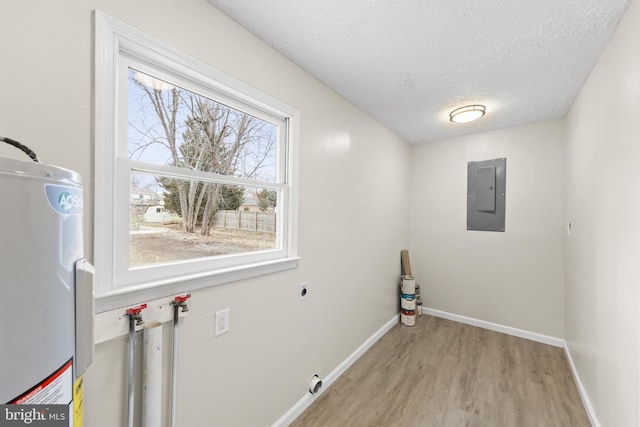 clothes washing area with water heater, light wood-style flooring, laundry area, electric panel, and baseboards