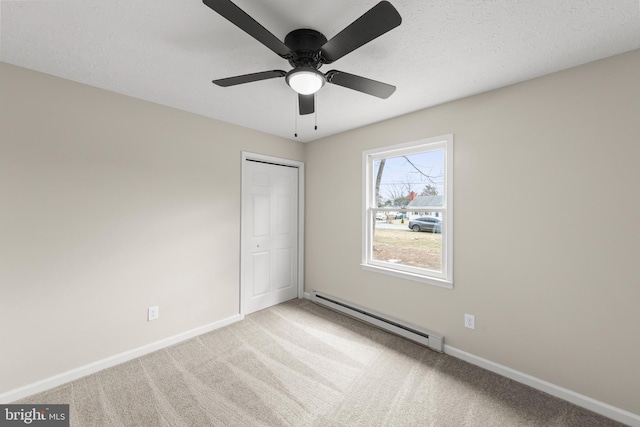 unfurnished bedroom with a textured ceiling, a baseboard heating unit, baseboards, a closet, and carpet