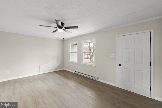 empty room with a baseboard radiator, a textured ceiling, visible vents, and wood finished floors