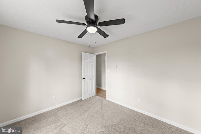 unfurnished room with a ceiling fan, baseboards, and carpet flooring