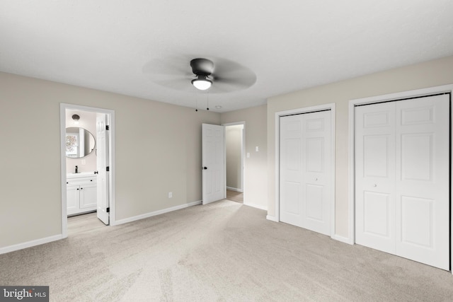 unfurnished bedroom featuring multiple closets, a ceiling fan, light carpet, connected bathroom, and baseboards