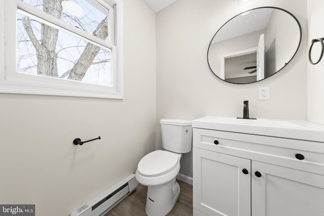 half bathroom with baseboard heating, toilet, vanity, wood finished floors, and baseboards