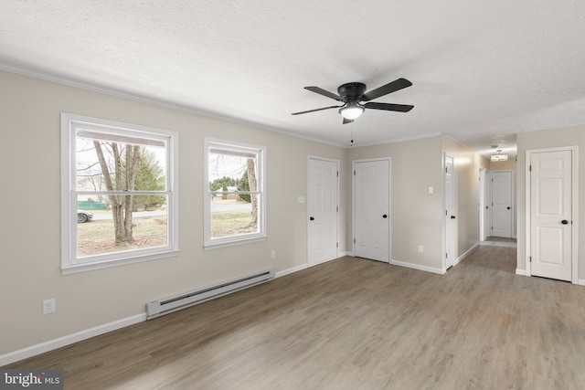 unfurnished living room with light wood-style floors, baseboards, baseboard heating, and a textured ceiling