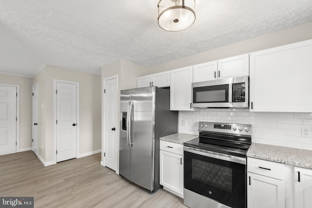 kitchen with light wood-style floors, white cabinetry, stainless steel appliances, and backsplash