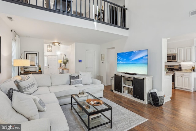 living room with baseboards, a high ceiling, visible vents, and dark wood-style flooring